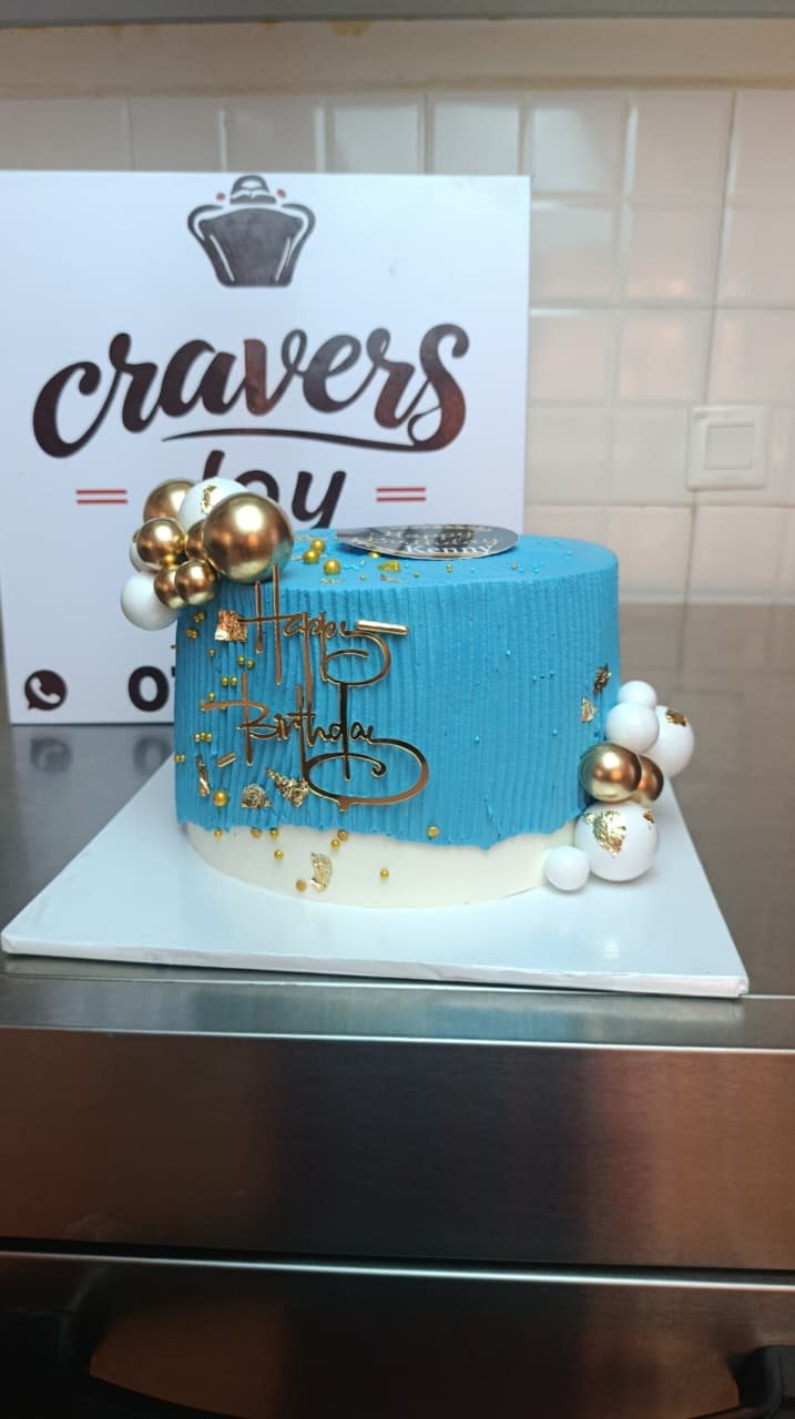 Ribbed buttercream birthday cake decorated with gold leaf and gold spheres.