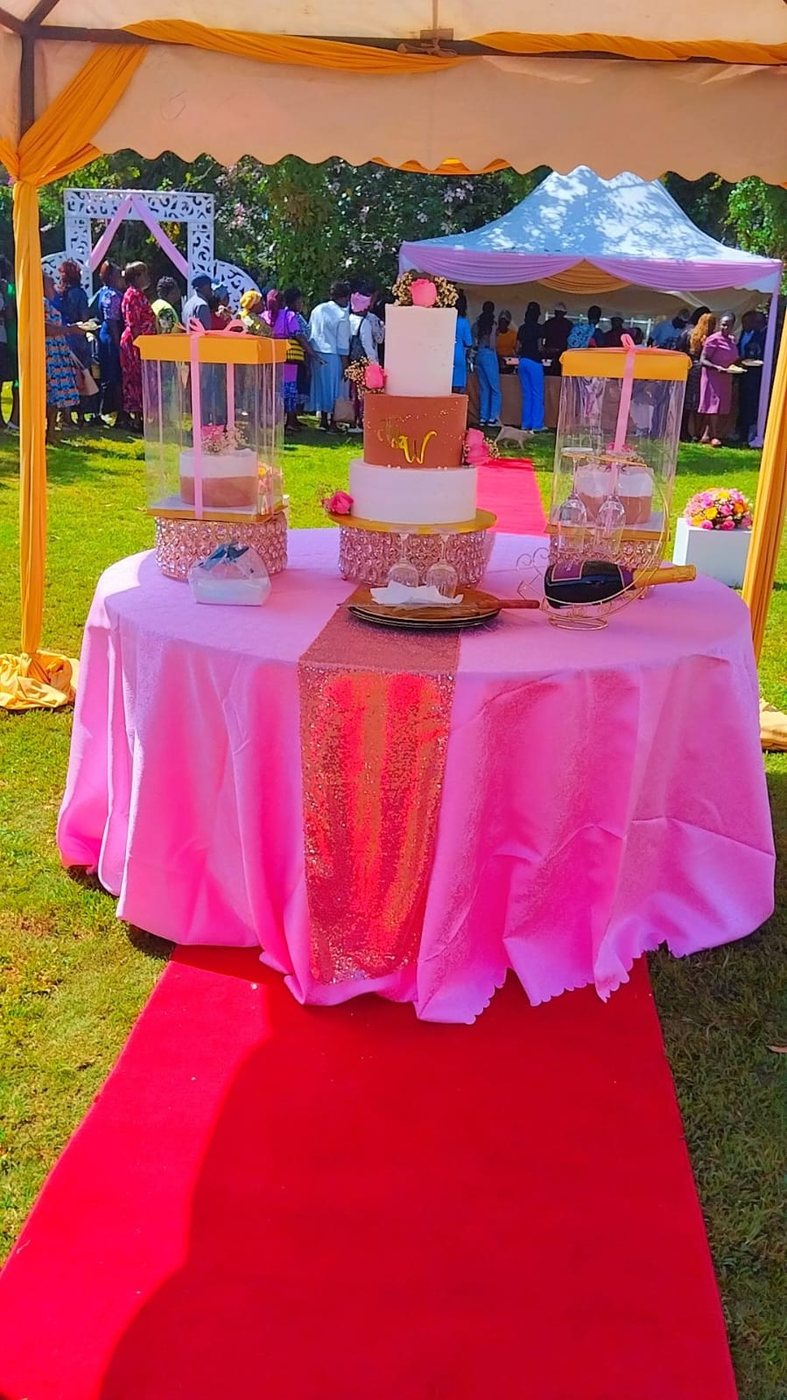 Three tier white wedding cake with rose gold detailing and a gold initial on the front tier.