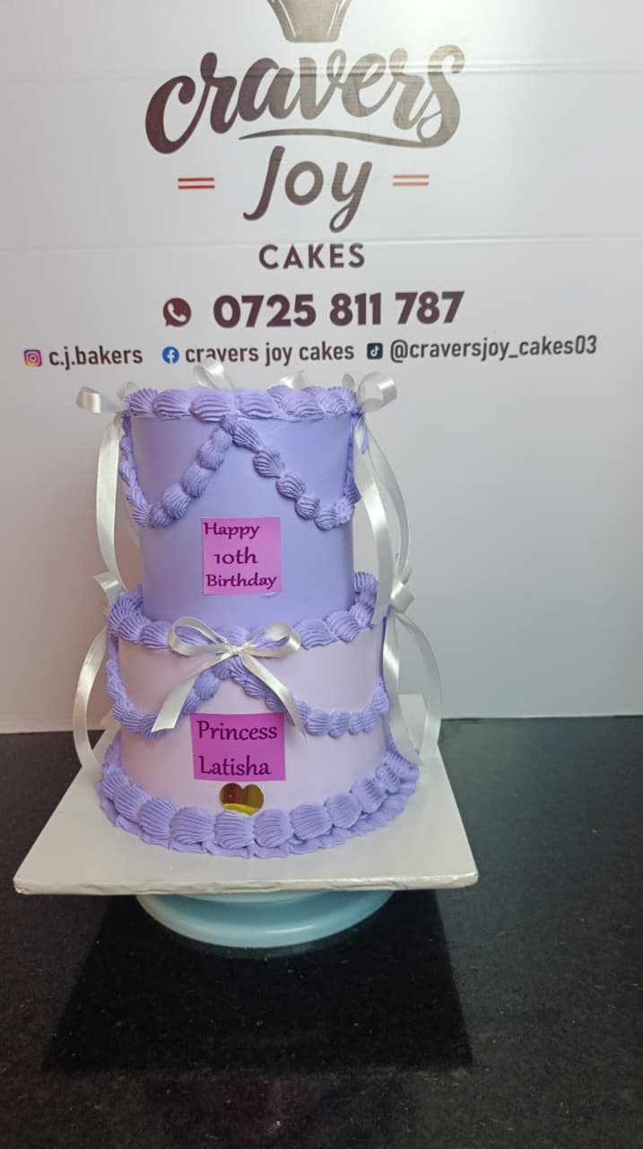 Two tier cake with vintage piping and ribbon bows in soft colours.