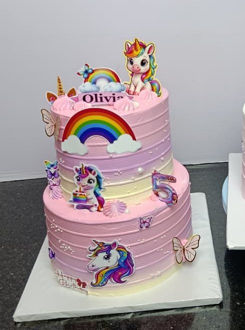 Pink and lilac children's cake with a unicorn topper, rainbows and butterflies.