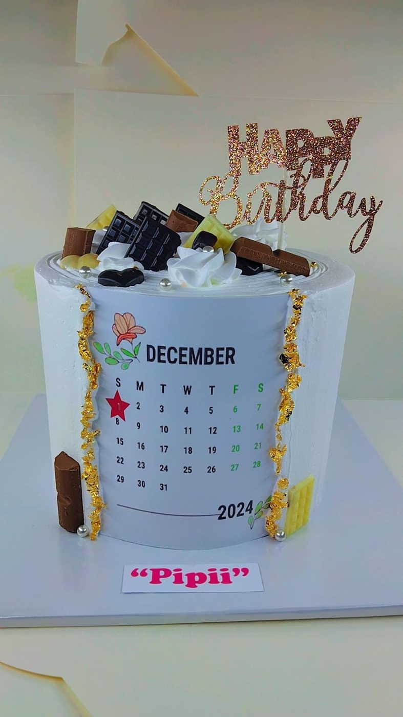 Cake printed with a calendar page, the date circled, topped with chocolate shards and gold leaf.