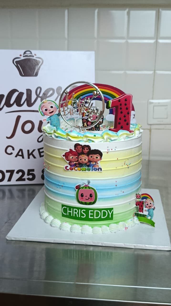 Children's cake with rainbow ombre bands, sprinkles and small figurine toppers.