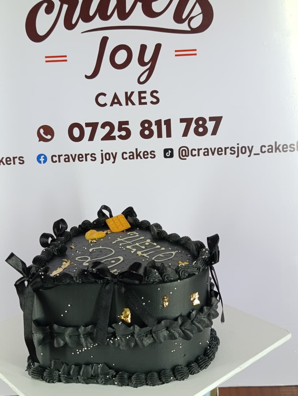 Black buttercream cake finished with satin bows and flecks of gold leaf.