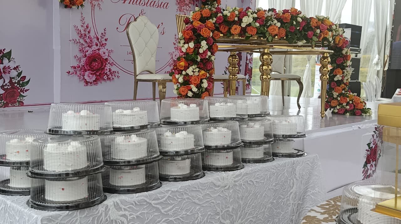 Rows of small boxed giveaway cakes sealed and stacked on a table at a ceremony.